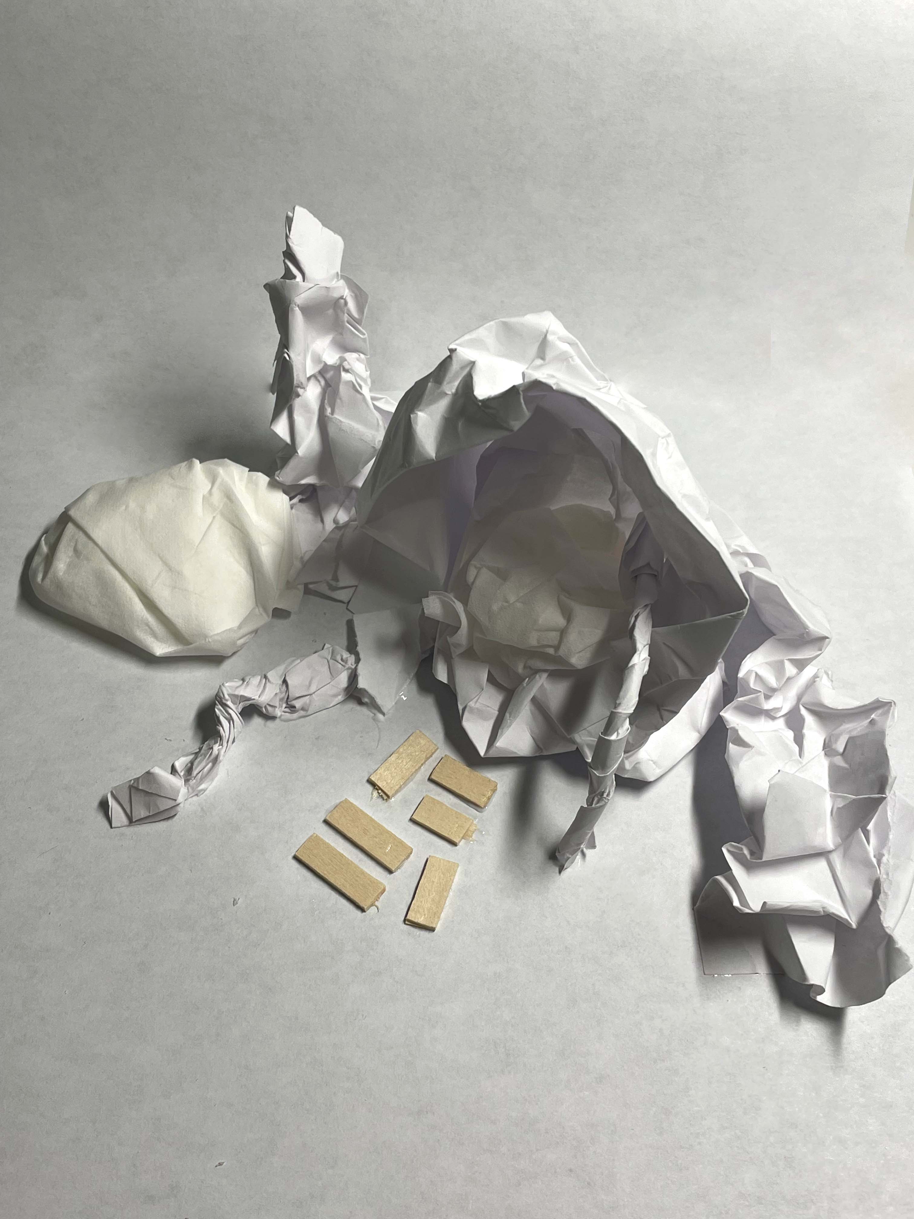 Paper model of seat with an awning, a guardrail, and a path. The seat has a cushion on the ground to its right.