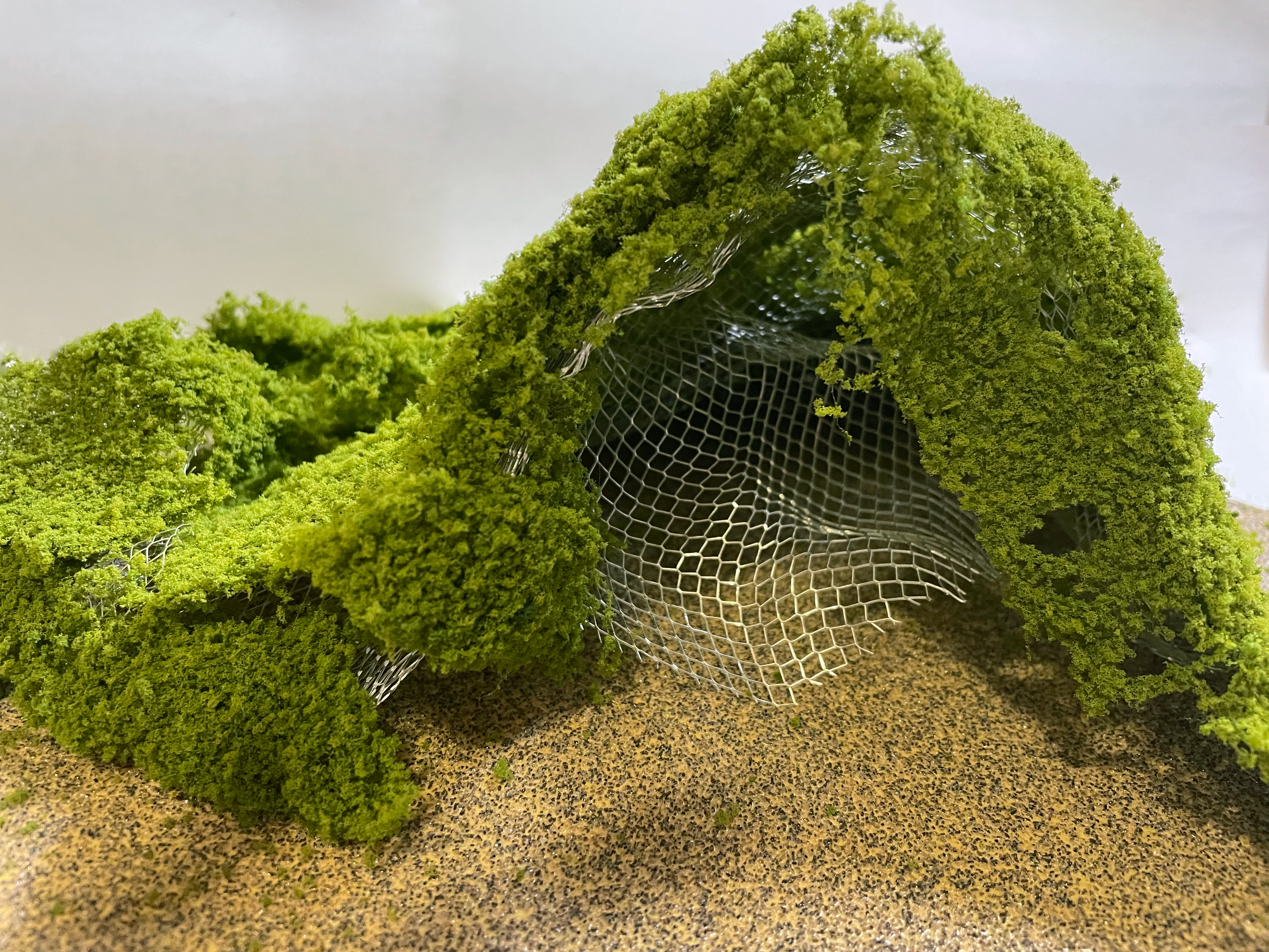 Wire model prototype with a green, foliage-like covering.