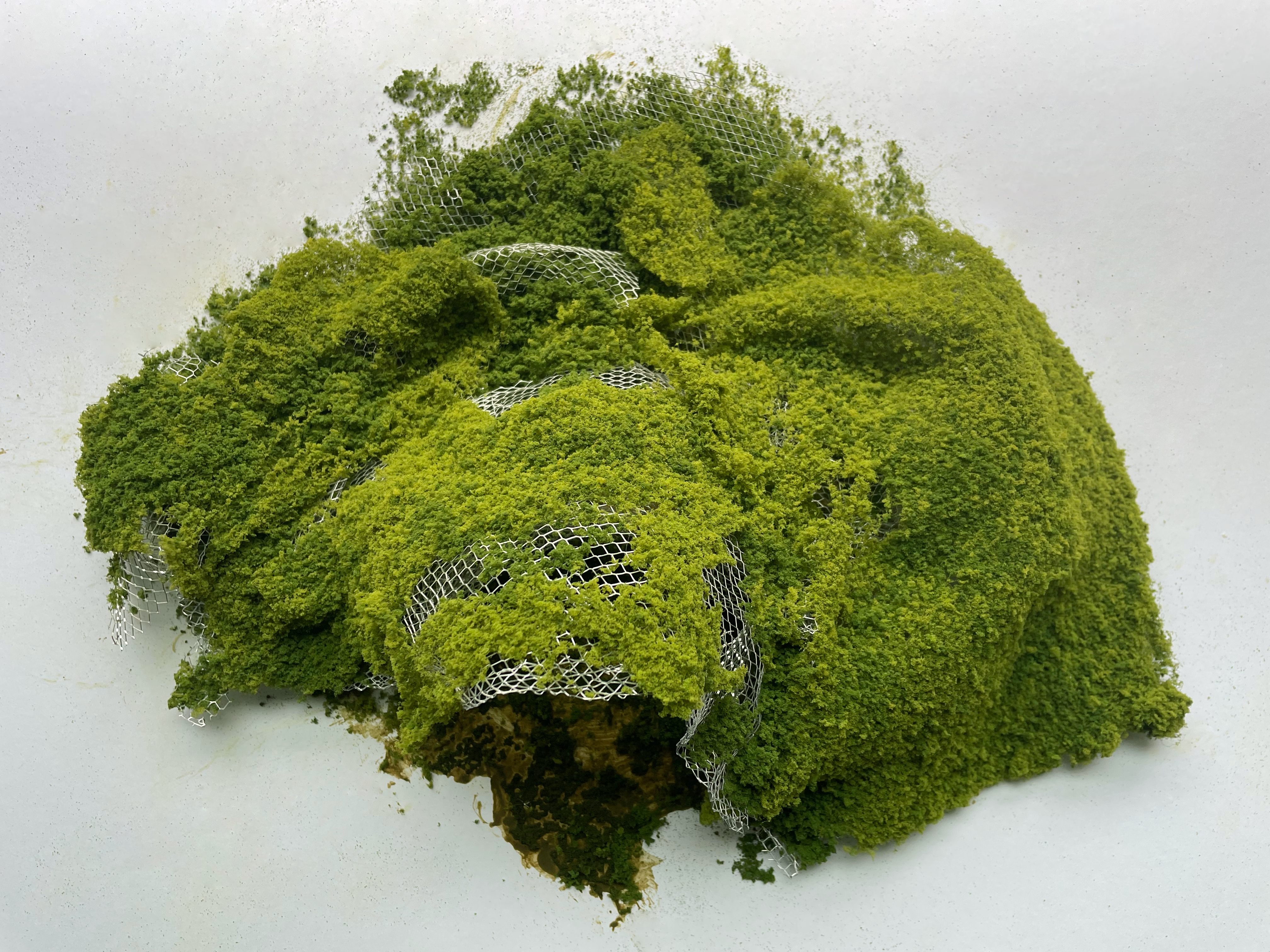 Bird's eye photo of a model of the project covered in green foliage.